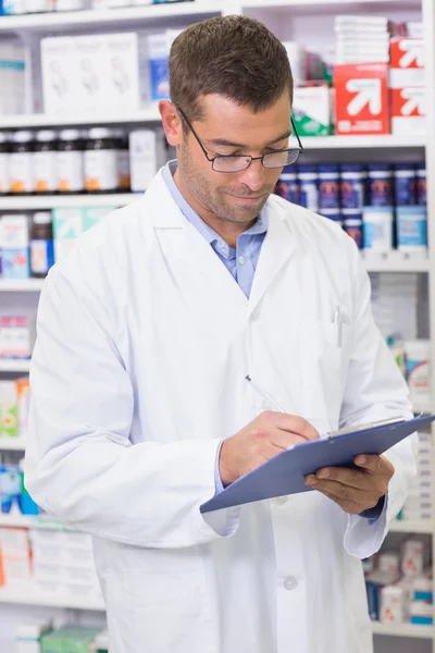 Farmacéutico enfocado escribiendo en portapapeles — Foto de Stock