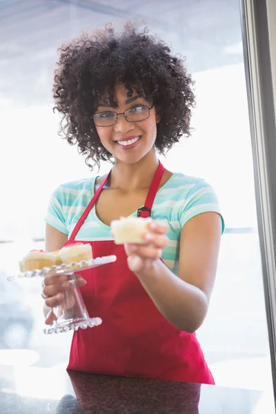 Medarbetaren leende och erbjuder cupcake — Stockfoto