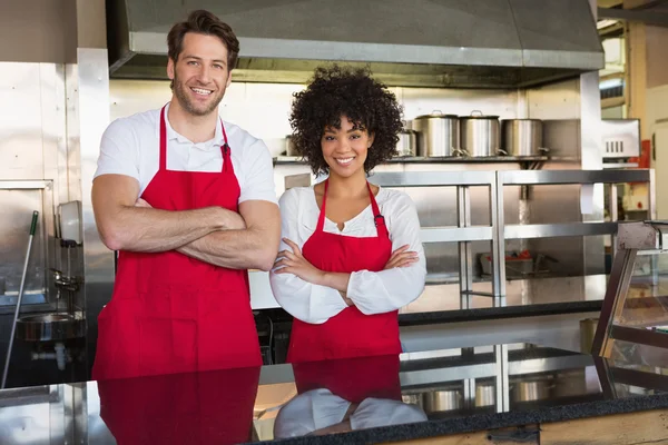 Colleagues in red apron with arms crossed — Stock Photo, Image