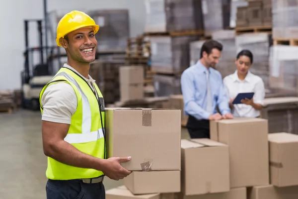 Worker carrying box in warehouse — Stock Photo, Image