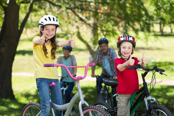Family on bike at park with thumbs up — Stock Photo, Image