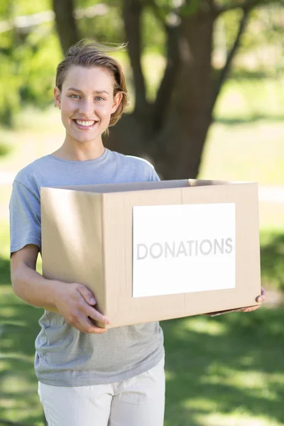 Happy volunteer in the park holding box — Stock Photo, Image