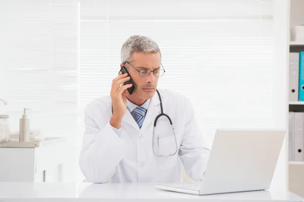 Doctor phoning and using computer — Stock Photo, Image