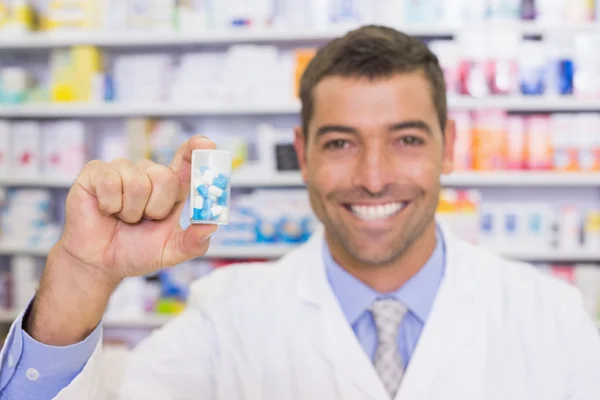 Farmacêutico bonito mostrando frasco remédio — Fotografia de Stock