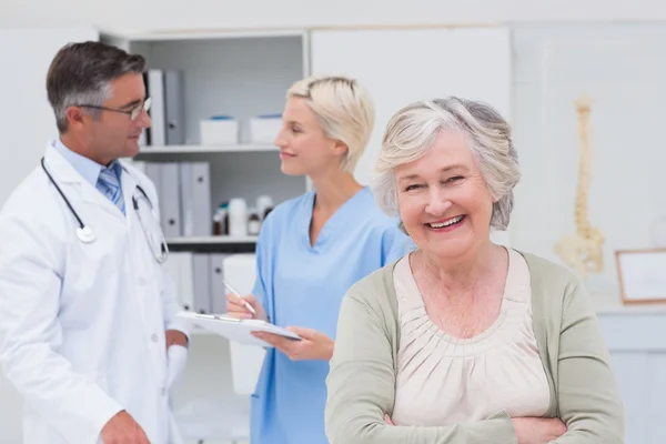 Paciente sonriendo mientras el médico y la enfermera discuten —  Fotos de Stock