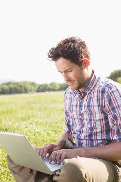 Homem usando laptop no campo — Fotografia de Stock