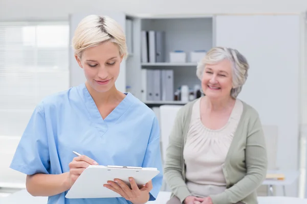 Krankenschwester schreibt auf Klemmbrett — Stockfoto