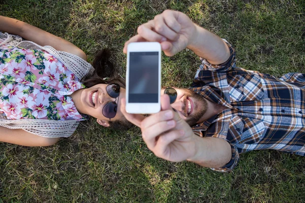 Para, leżąc na trawie przy selfie — Zdjęcie stockowe