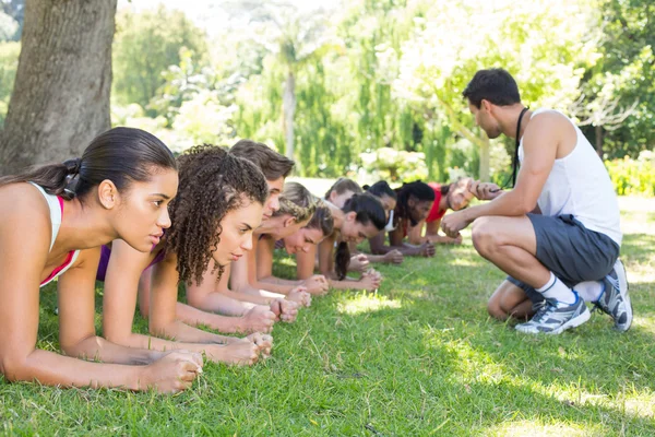 Fitness groep planking in park met coach — Stockfoto