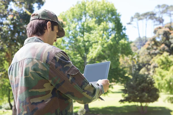 Солдат смотрит на планшетный компьютер в парке — стоковое фото
