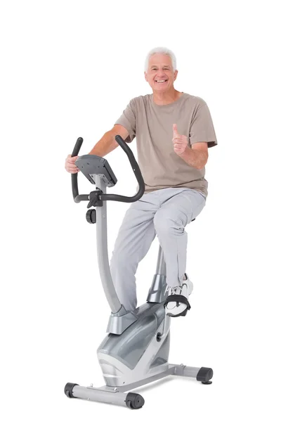 Senior man on exercise bike — Stock Photo, Image