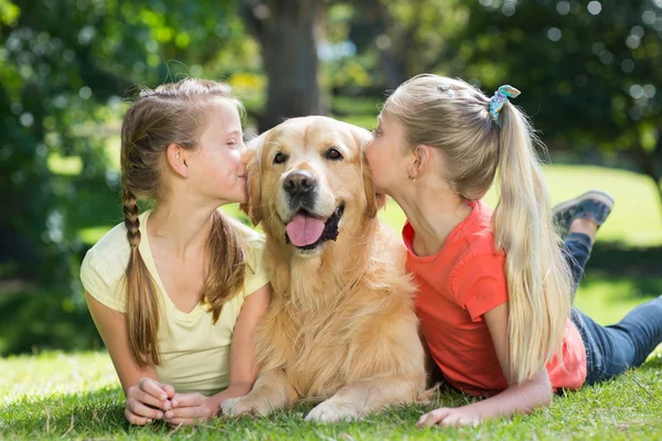 Sisters kissing their dog in the park — Stock Photo, Image