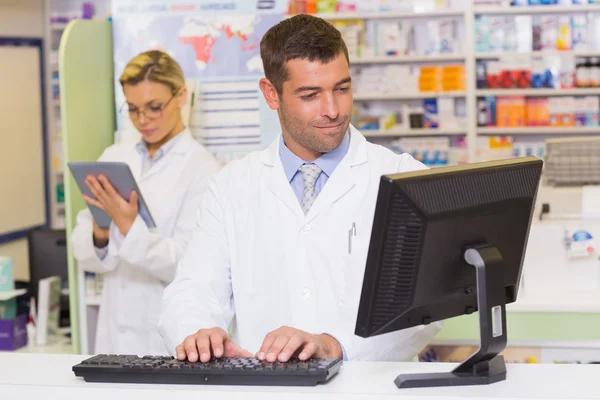 Smiling pharmacist using computer — Stock Photo, Image