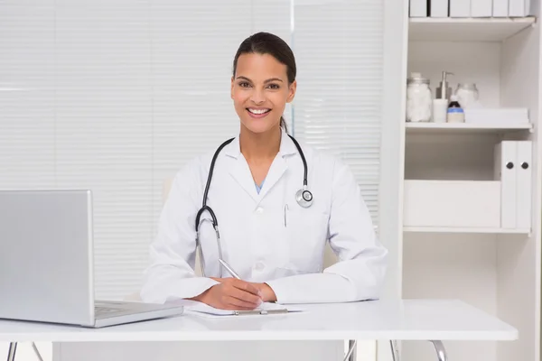 Morena doctor escribiendo en portapapeles — Foto de Stock