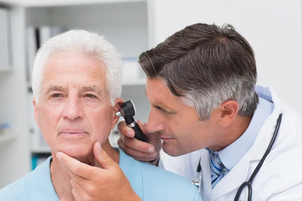 Doctor examining senior patients ear — Zdjęcie stockowe