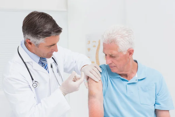 Doctor injecting senior patient in clinic — Stock Photo, Image