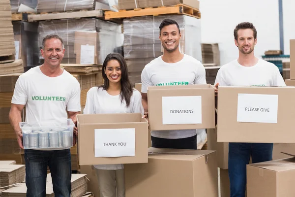 Voluntarios sonriendo a la cámara sosteniendo cajas de donaciones — Foto de Stock