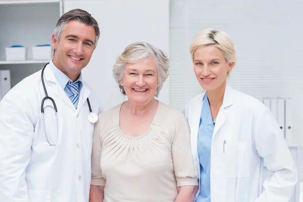 Artsen en senior patiënt glimlachend in kliniek — Stockfoto