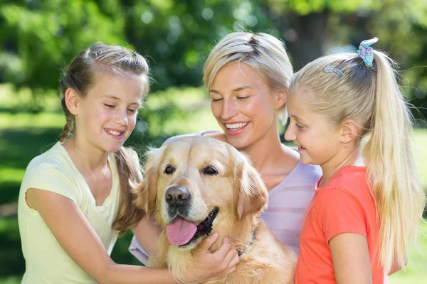 Счастливая семья играет со своей собакой — стоковое фото