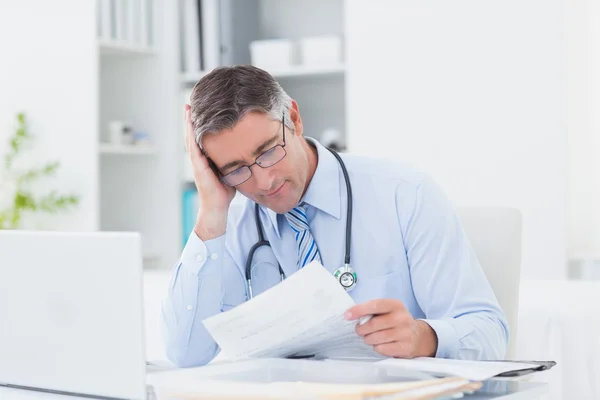 Tensed male doctor reading document — Stock Photo, Image