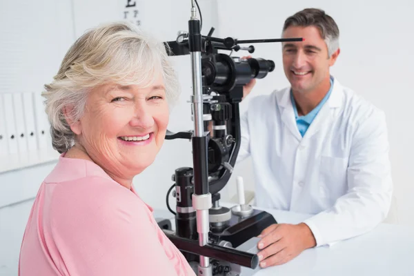 Woman smiling while sitting with optician — Stock Photo, Image