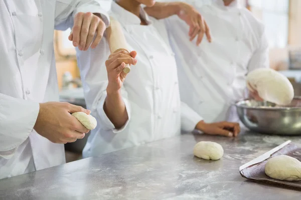 Colleagues holding rolling pin and dough — Stock Photo, Image