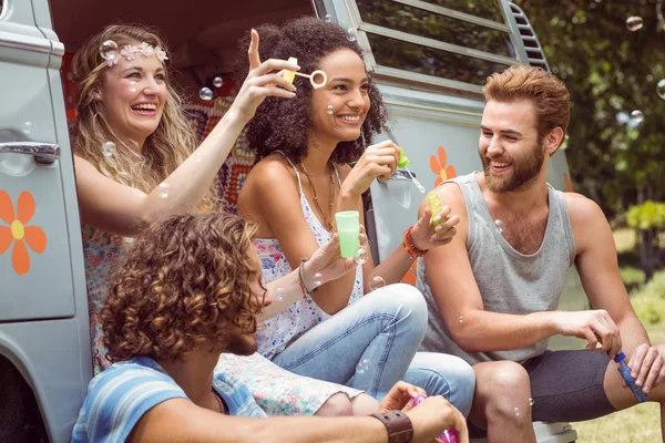 Hipsters blowing bubbles in camper van — Stock Photo, Image