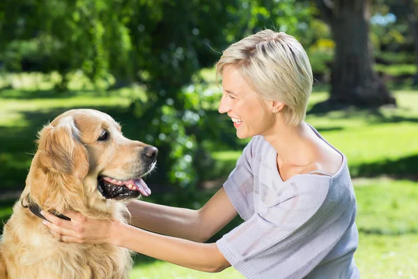 Loira brincando com o cão no parque — Fotografia de Stock