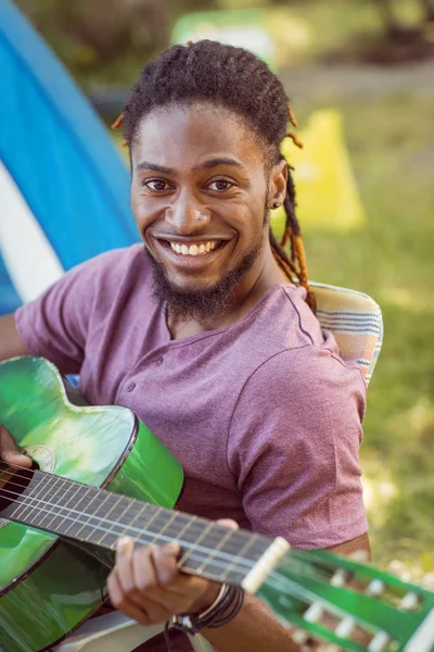 Hipster χαμογελώντας σε φωτογραφική μηχανή παίζει κιθάρα — Φωτογραφία Αρχείου