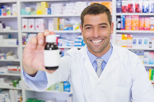 Bonito farmacêutico mostrando frasco de medicamento — Fotografia de Stock