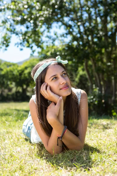 Mooie brunette denken op het gras — Stockfoto