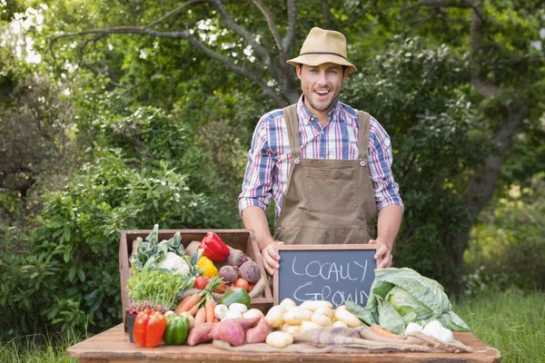 Happy farmář ukazující jeho produkce — Stock fotografie