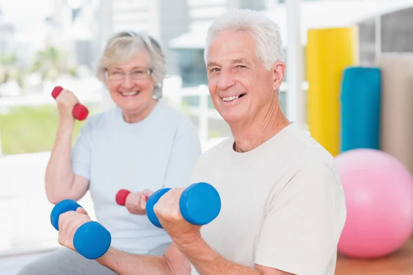 Senior couple lifting dumbbells in gym — Stock Photo, Image