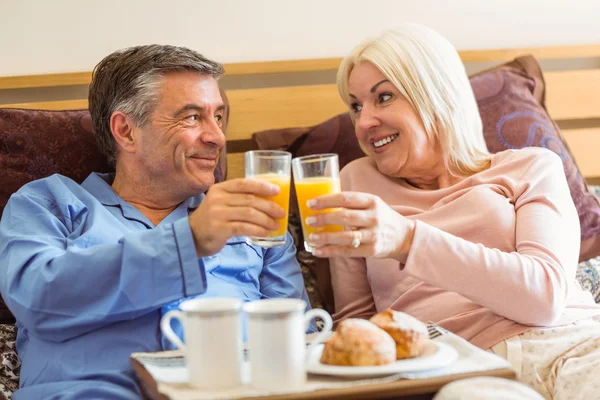 Feliz casal maduro tomando café da manhã na cama — Fotografia de Stock