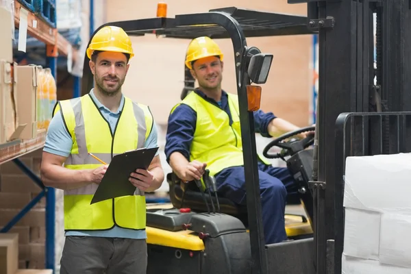 Trabajador de almacén sonriente y conductor de carretilla elevadora — Foto de Stock