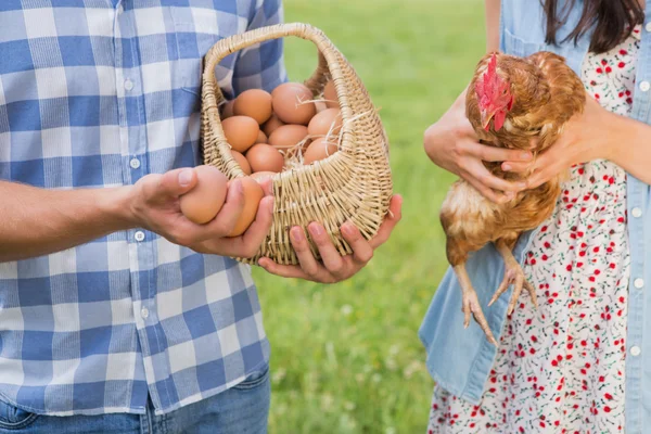 Счастливые фермеры держат курицу и яйца — стоковое фото