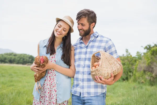 Mutlu çiftçiler holding tavuk ve yumurta — Stok fotoğraf