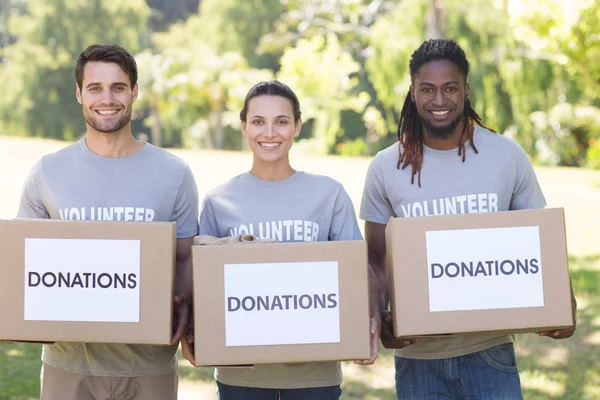 Felices voluntarios con cajas de donaciones en el parque — Foto de Stock