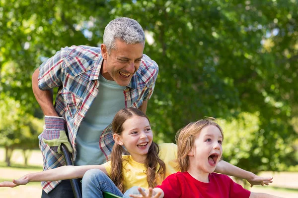 Pappa och hans barn som leker med skottkärra — Stockfoto