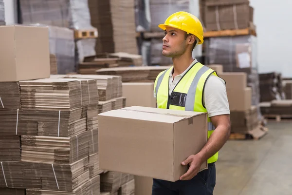 Worker carrying box in warehouse — Stock Photo, Image