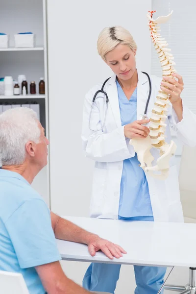 Médico explicando modelo de columna vertebral al paciente — Foto de Stock