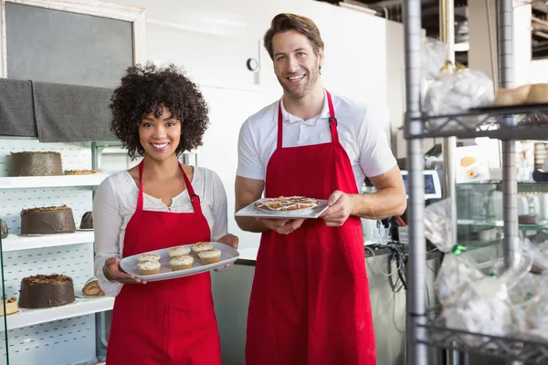 Smiling colleagues showing plate of desert — Stock Photo, Image