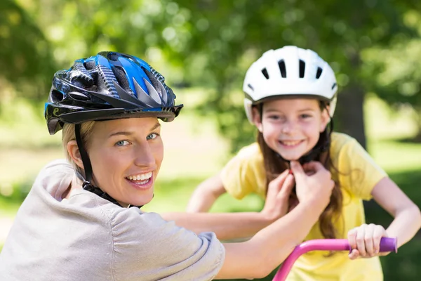 Mãe anexando suas filhas ciclismo capacete — Fotografia de Stock