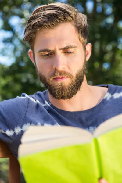 Молодий чоловік читає на лавці парку — стокове фото