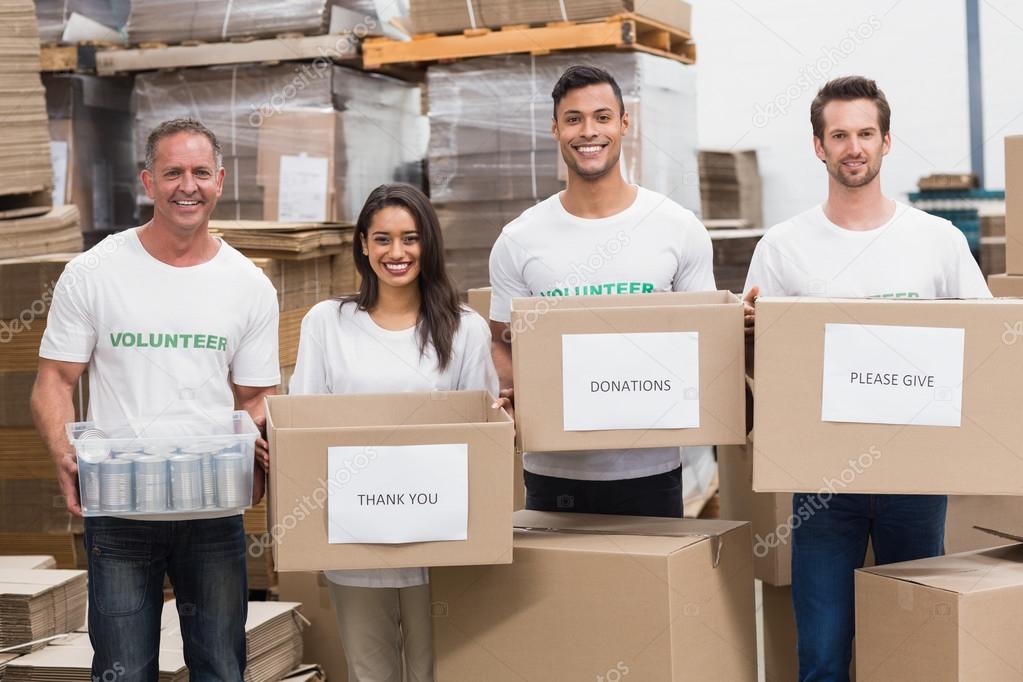 Volunteers smiling at camera holding donations boxes — Stock Photo