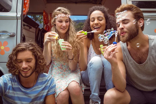 Hipsters blowing bubbles in camper van — Stock Photo, Image