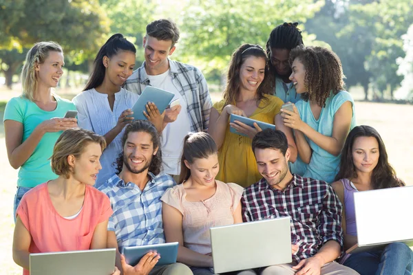 Amici sorridenti utilizzando dispositivi multimediali — Foto Stock