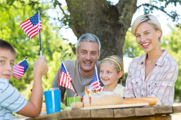 家族のピクニックを持つとアメリカの国旗を保持しています。 — ストック写真