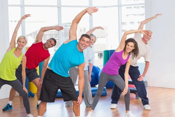 Ajustar a la gente haciendo ejercicio de estiramiento en el gimnasio —  Fotos de Stock