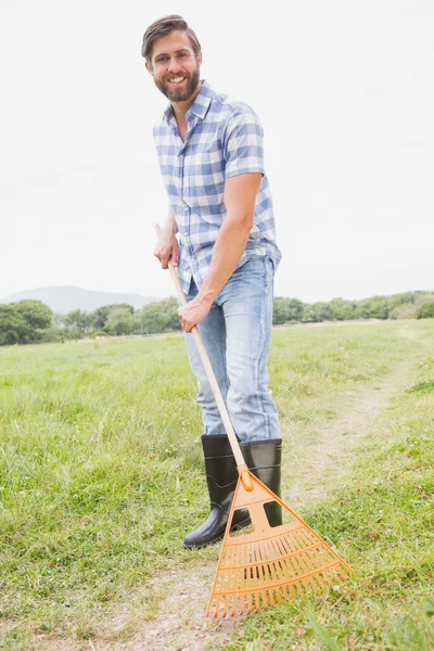 Hombre feliz rastrillando su granja —  Fotos de Stock